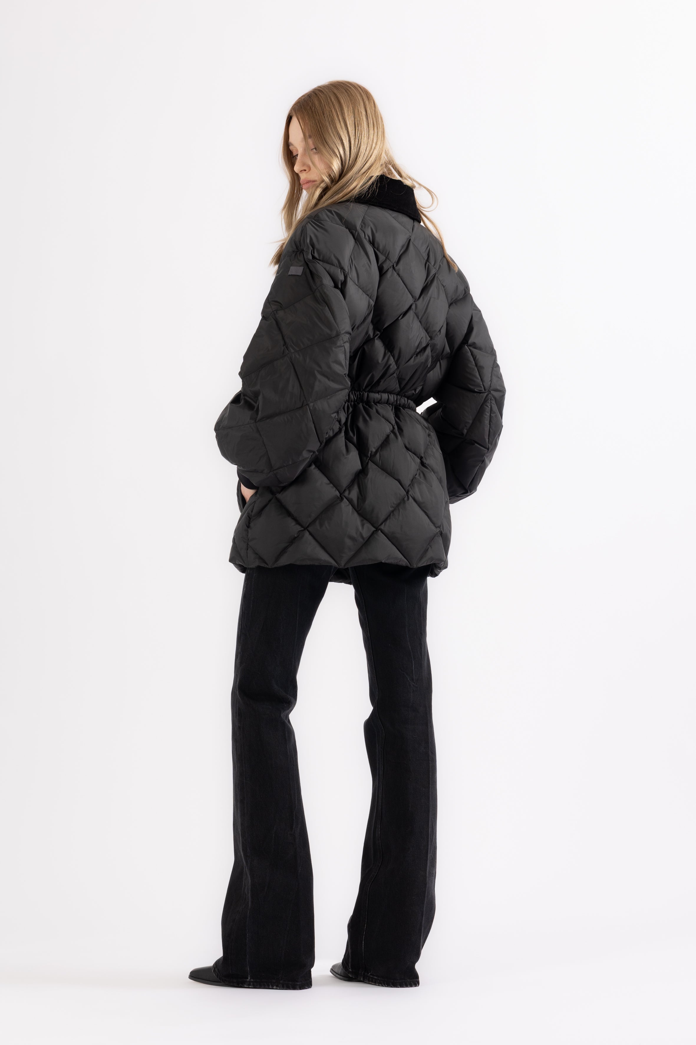 Person wearing a black quilted jacket on a white background