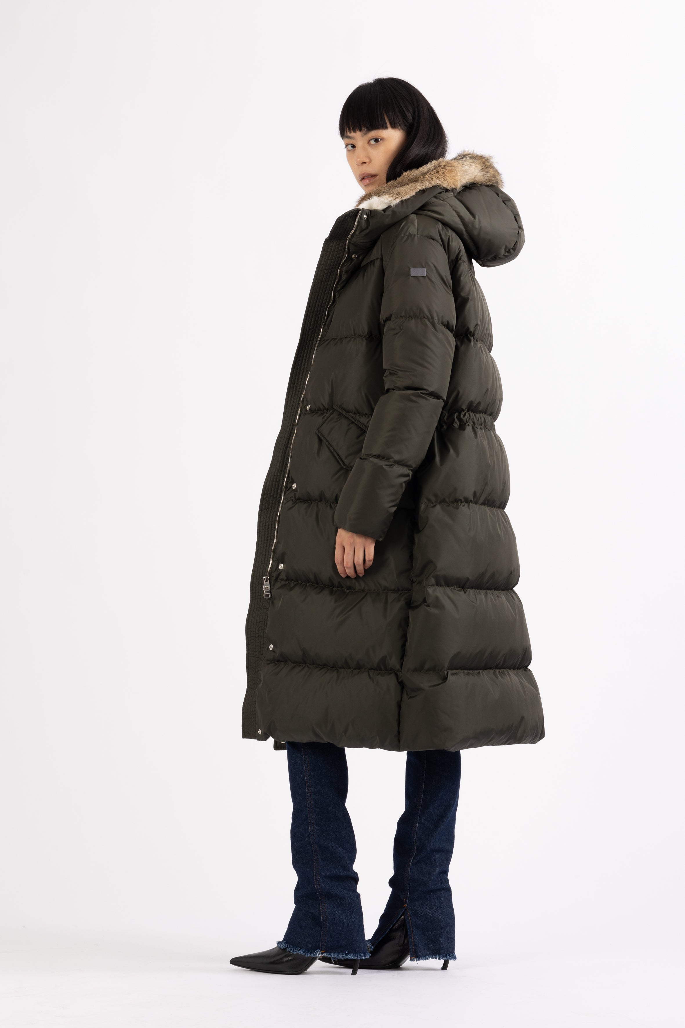 Long Lempelius Downcoat with a slim, slightly flared silhouette in dark green
and hood with extra soft, removable rabbit fur