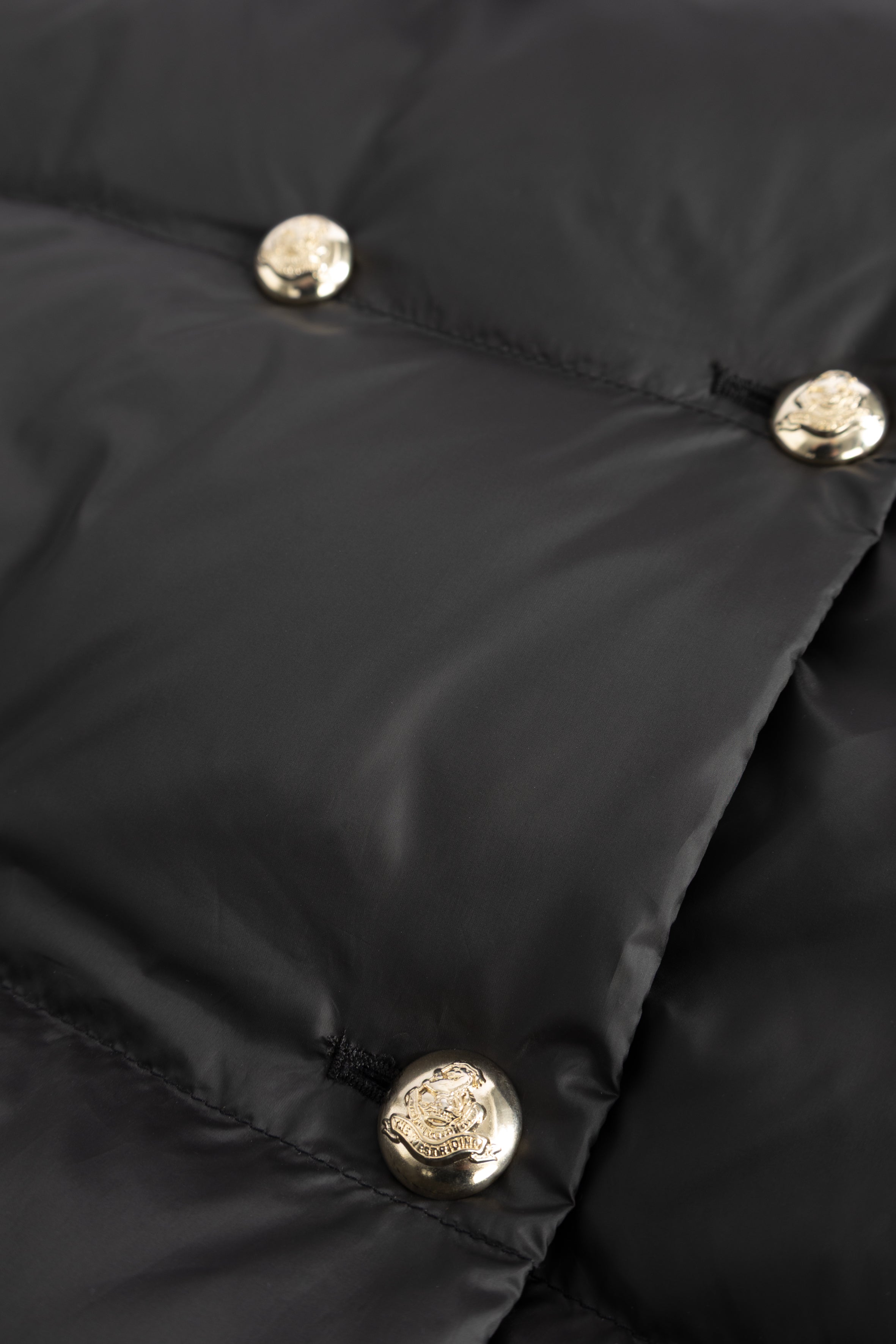 Close-up of a black puffer jacket with gold buttons