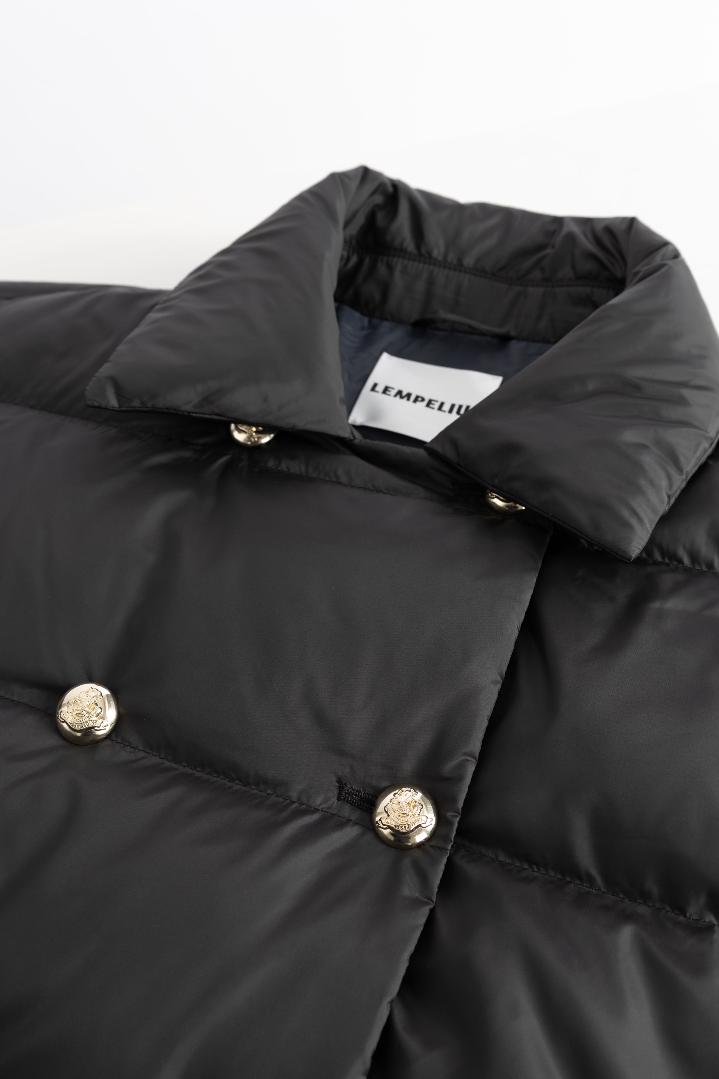 Close-up of a black puffer jacket 270GO ADA with gold buttons on a white background