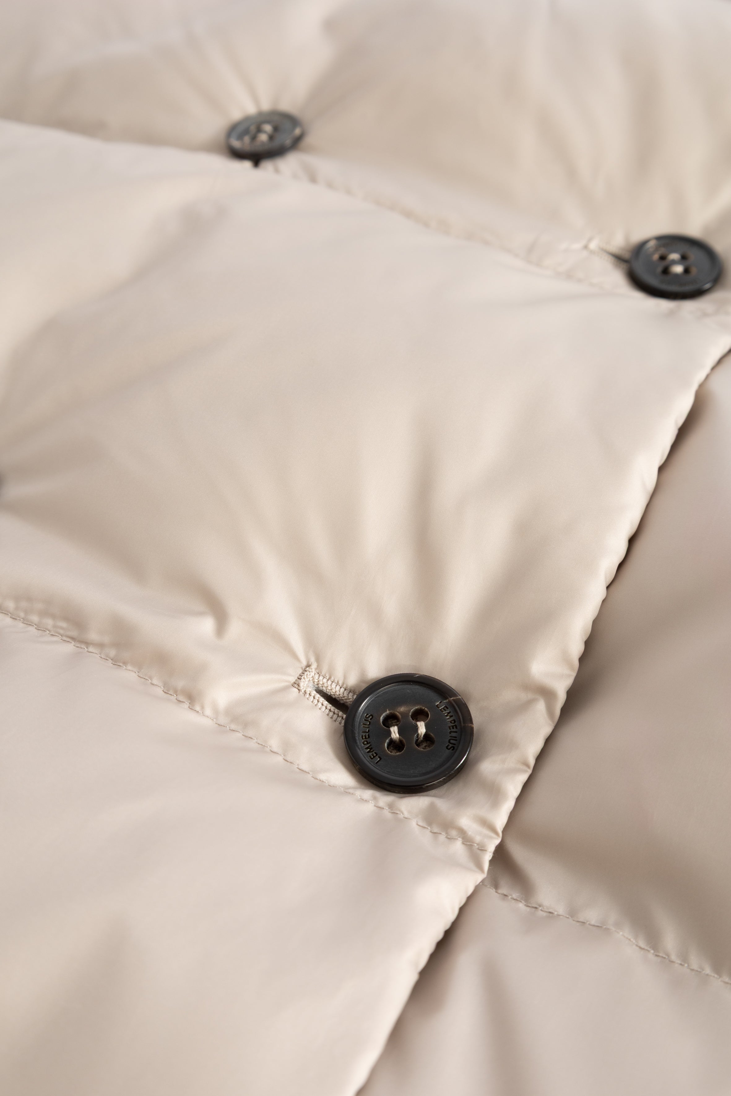 Close-up of beige puffer jacket with dark buttons