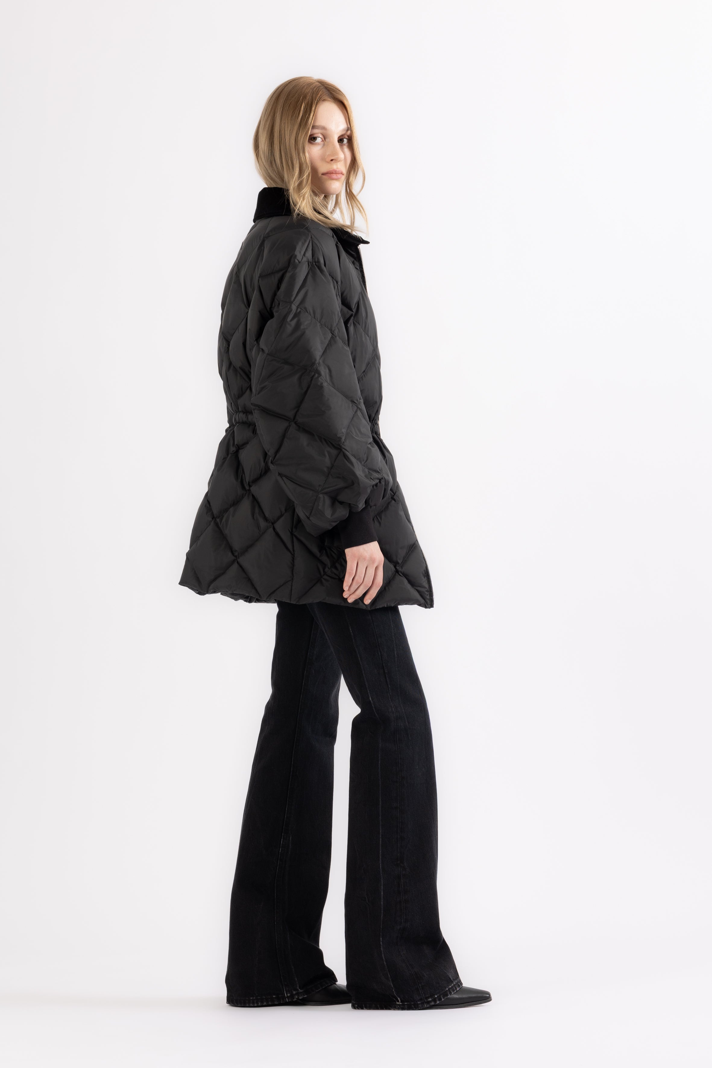 Woman wearing a black quilted jacket and pants on a white background